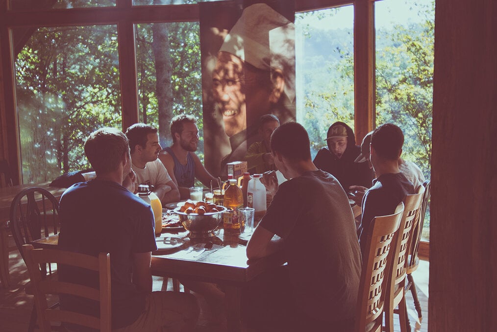 a group of people sitting around the dinner table eating 